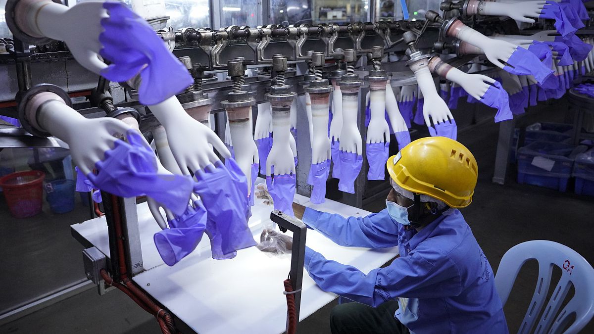 عامل يتفقد القفازات التي تستخدم لمرة واحدة في مصنع توب غلوف خارج كوالالمبور، ماليزيا.