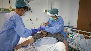 A doctor and colleague place an oxygen mask on a man in the COVID-19 section at the University Emergency Hospital in Bucharest, Romania, Friday, Oct. 22, 2021.