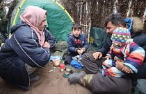 A family eat at a tent camp as migrants gather at the Belarus-Poland border near Grodno, Belarus, Saturday, Nov. 13, 2021.