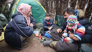 A family eat at a tent camp as migrants gather at the Belarus-Poland border near Grodno, Belarus, Saturday, Nov. 13, 2021.