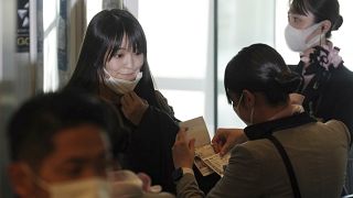 Japan's former Princess Mako, left, the elder daughter of Crown Prince Akishino, takes her mask off at a boarding gate to board an airplane to New York, 14 November 2021.