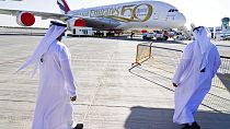 Two Emiratis walk toward an Emirates Airbus A380 jumbo jet on display at the Dubai Air Show in Dubai