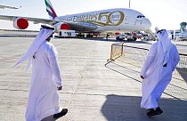 Two Emiratis walk toward an Emirates Airbus A380 jumbo jet on display at the Dubai Air Show in Dubai