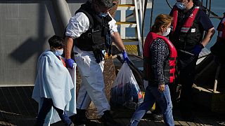 Мигранты сходят с патрульного катера британских пограничных войск в гавани Дувра