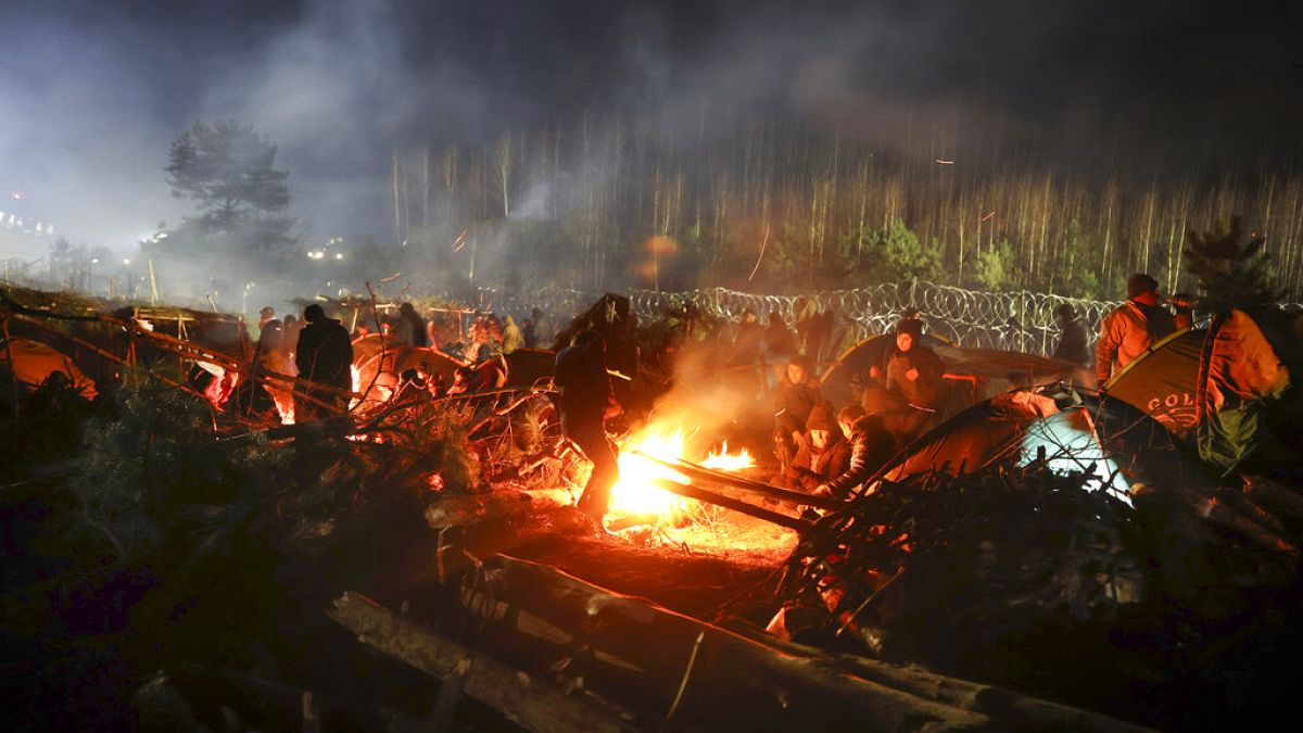 Los migrantes se calientan junto a una hoguera mientras se reúnen en la frontera entre Bielorrusia y Polonia, cerca de Grodno, Bielorrusia, el sábado 13 de noviembre de 2021