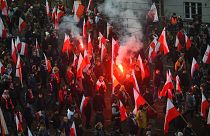 People hold Polish flags, as smoke from flares lit by members of far-right groups rises above the annual Independence Day march in Warsaw, Poland, Nov. 11, 2021.