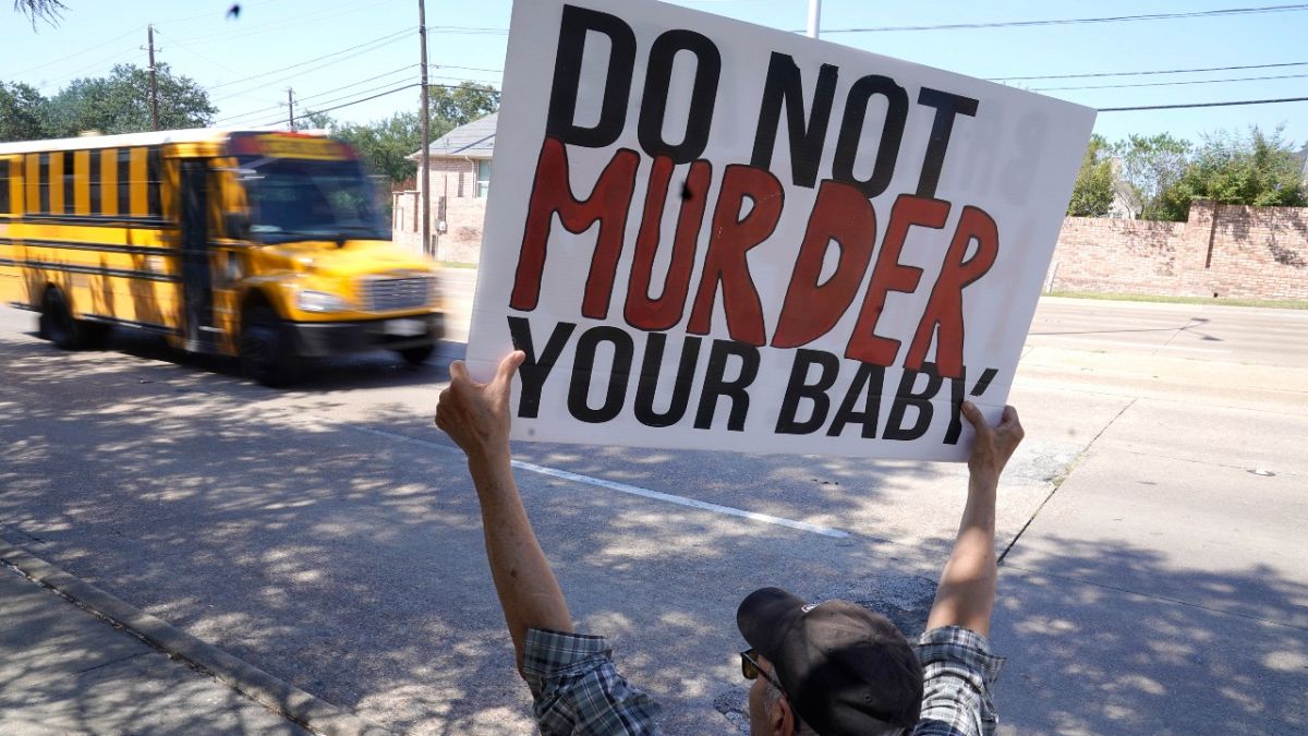 رجل يحمل لافتة مكتوب عليها " لا تقتل طفلك" أمام عيادة تقدم خدمات إجهاض في دالاس، تكساس.