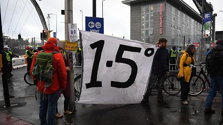 A protester holds a banner displaying a "1.5 degree" slogan during a climate change demonstration outside of the COP26.