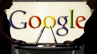 Exhibitors work on laptop computers in front of an illuminated sign of the Google logo at the industrial fair Hannover Messe in Hanover, Germany, April 17, 2007