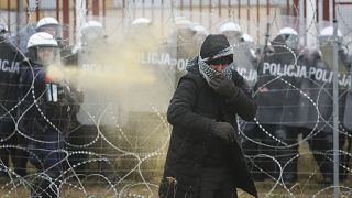 Polish serviceman sprays tear gas during clashes between migrants and Polish border guards at the Belarus-Poland border near Grodno, Belarus, on Tuesday, Nov. 16, 2021