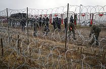 Militari polacchi dall'altra parte della recinzione di filo spinato al checkpoint di Kuznica, al confine tra Bielorussia e Polonia