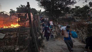  لاجئون ومهاجرون يحملون أمتعتهم يفرون من حريق مشتعل في مخيم موريا ، في جزيرة ليسبوس ، اليونان 9 سبتمبر، 2020