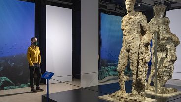 Visitor observes Hermes statue at new exhibition