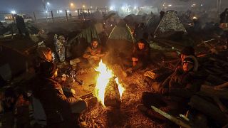 Migrants warm themselves near a fire as they gather at the checkpoint "Kuznitsa" at the Belarus-Poland border near Grodno, Belarus, on Wednesday, Nov. 17, 2021.