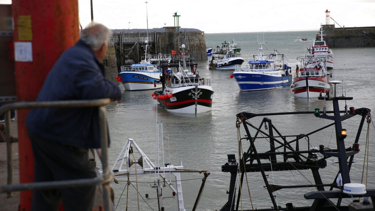 A man watches trawlers arriving in the port of Granville, Normandy, Thursday, Nov. 4, 2021.