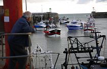 A man watches trawlers arriving in the port of Granville, Normandy, Thursday, Nov. 4, 2021.