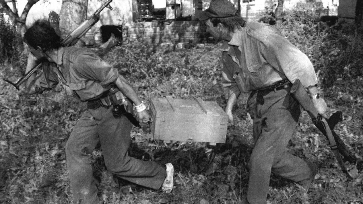 Dos soldados territoriales serbios corren con una caja de granadas capturada en las afueras de la ciudad de Vukovar, Croacia, el viernes 27 de septiembre de 1991
