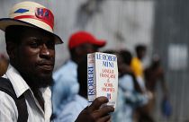 A man carries a paperback French dictionary "Le Robert Mini".