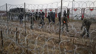 Polish servicemen stand behind a barbed wire fence at the "Kuznitsa" border checkpoint.