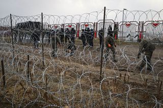 Polish servicemen stand behind a barbed wire fence at the "Kuznitsa" border checkpoint.