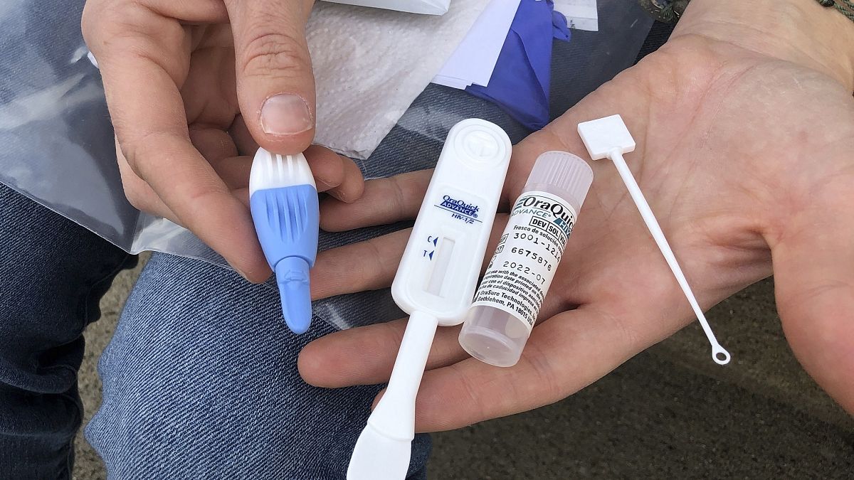 In this March 9, 2021 file photo, Solutions Oriented Addiction Response organizer Brooke Parker holds an HIV testing kit in Charleston, W.Va.