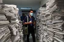 European Union Election Observation Mission member Rocco Dibiase walks past a stack of newsletters listing candidate names in Los Teques, Venezuela