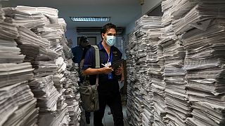 European Union Election Observation Mission member Rocco Dibiase walks past a stack of newsletters listing candidate names in Los Teques, Venezuela