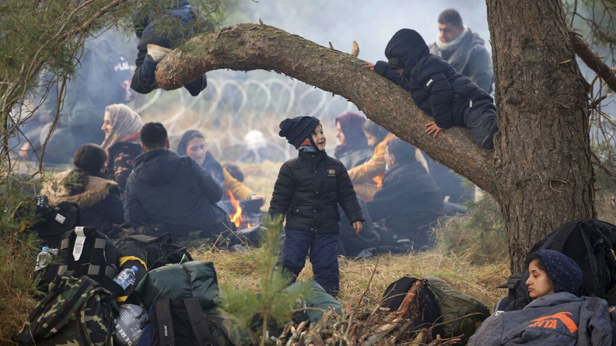 Migrants from the Middle East and elsewhere rest on the ground as they gather at the Belarus-Poland border near Grodno, Belarus, Monday, Nov. 8, 2021.
