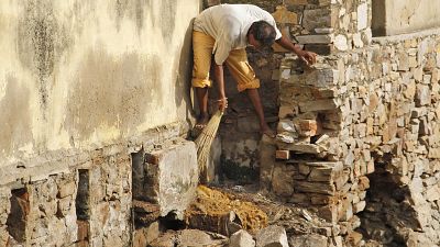 In this Aug. 26, 2014 file photo, a low-caste sweeper cleans excreta flowing out of a public toilet at Ajmer, India.