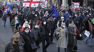 Demonstrators hold Georgian national and EU flags as they march during a rally in support of former President Mikheil Saakashvili in Tbilisi, Georgia, Friday, Nov. 19, 2021. 