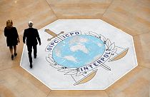 In this photo taken on Thursday, Nov.8, 2018 people walk on the Interpol logo at the international police agency headquarters in Lyon, central France