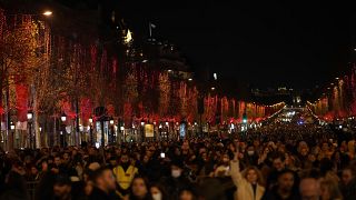 Spectators gather to attend the Champs Elysee Avenue illumination ceremony for the Christmas season, in Paris, Sunday, Nov. 21, 2021.