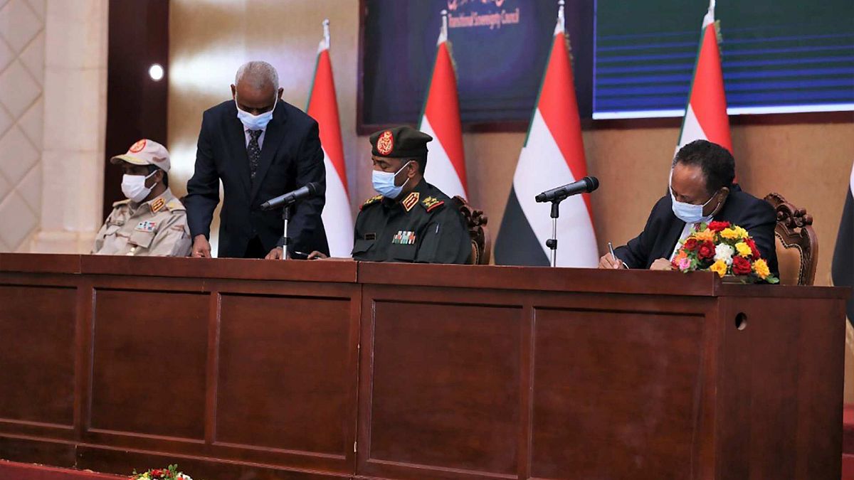 عبد الله حمدوك الذي أطيح به في انقلاب الشهر الماضي، يجلس إلى جانب اللواء عبد الفتاح البرهان، لتوقيع اتفاق يعيده رئيسا للوزراء، بالخرطوم، السودان، الأحد 21 نوفمبر 2021