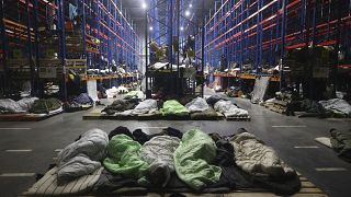 Migrants sleep at a logistics centre at the checkpoint "Kuznitsa" at the Belarus-Poland border near Grodno, Belarus, Monday, Nov. 22, 2021.