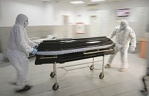 FILE - Funeral house employees drag a coffin on a trolley to take a COVID-19 victim for burial, in Bucharest, Romania, November 8, 2021.