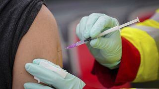 A person is vaccinated with the Pfizer vaccine against the coronavirus and the COVID-19 disease at vaccination bus in Berlin, Germany, Tuesday, Nov. 23, 2021.
