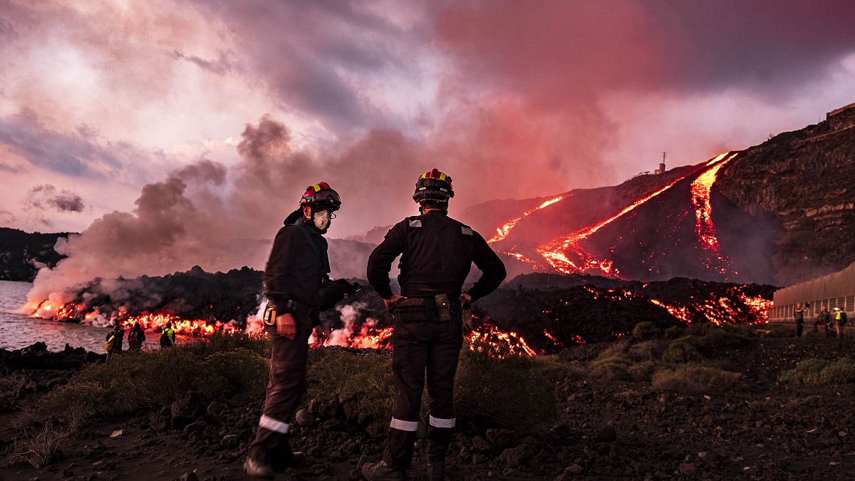 Members of UME (Military Emergency Unit) stand as lava flows from a volcano reaching the sea on the Canary island of La Palma, Spain, Thursday, Nov. 11, 2021.