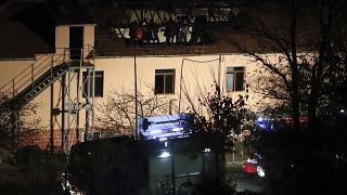 Police and investigators are seen on the burned roof at the nursing home in Royak.