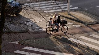 A woman and two children commute in Amsterdam, Netherlands, Tuesday, Nov. 23, 2021.