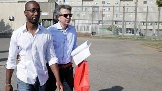 Rudy Guede, left, is greeted by an unidentified person as he leaves the penitentiary for a temporary release of thirty-six hours, in Viterbo, Italy, on June 25, 2016.