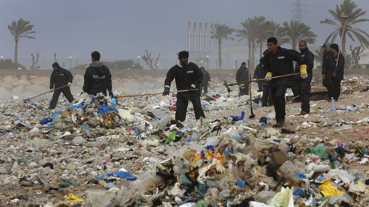 عمال ينظفون الشاطئ من القمامة شمال بيروت، لبنان. 