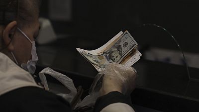 A woman changes Turkish lira for USD and Euro at a currency exchange shop, in Ankara, Turkey, Tuesday, Nov. 23, 2021.