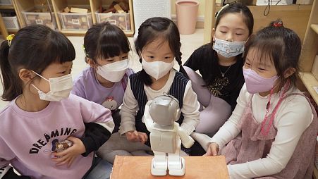 Students interact with a 24.5 centimetre (9.6 inch) tall "Alpha Mini" robot