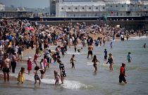 People venture into the sea as they enjoy themselves during a hot day on Brighton Beach.