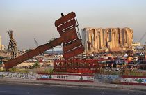 نصب يمثل العدالة يقف أمام آثار الانفجار الهائل في أغسطس/ آب 2020 في بيروت، لبنان.