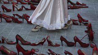 Una actriz camina cerca de una fila de zapatos rojos que representan a las mujeres asesinadas, 9/3/2020, Ciudad de México, México 