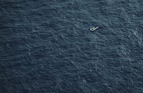 A partially deflated and empty rubber dinghy floats in the Mediterranean Sea between Libya and Italy.