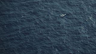 A partially deflated and empty rubber dinghy floats in the Mediterranean Sea between Libya and Italy.
