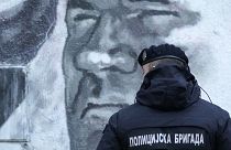 A police officer stands by a mural of former Bosnian Serb military chief Ratko Mladić in Belgrade, Serbia, Tuesday, Nov. 9, 2021.