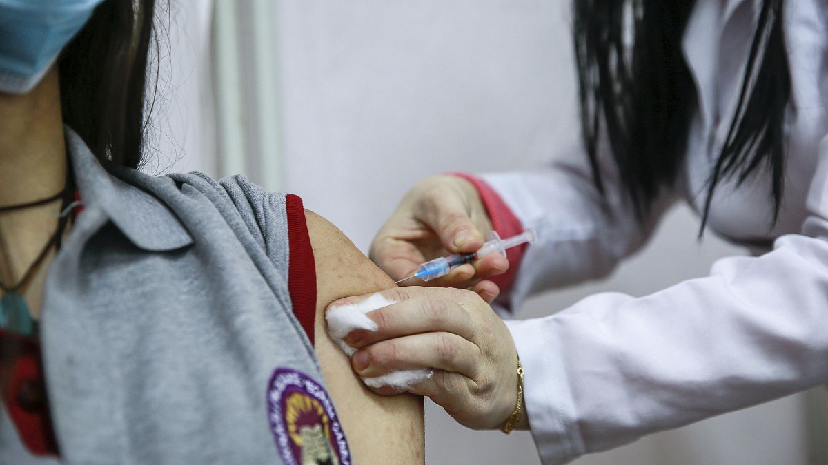 A high school student at Eqrem Qabej school is given a shot of a COVID-19 vaccine by a health official, in Pristina, Kosovo, Friday, Nov. 26, 2021.